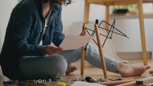Une jeune femme étudie indépendamment les instructions pour assembler des meubles pendant l'assemblage
