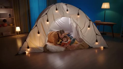 Adult and Child Reading in Glowing Indoor Tent