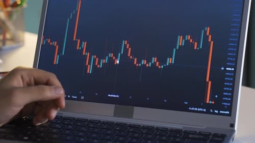 Male closely following stock market and cryptocurrency charts on laptop.