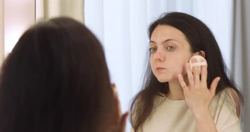 Woman Applying Makeup in Front of Mirror