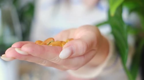 Woman Holds Nutritional Gel Capsules in Her Hand