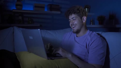 Young Adult Typing on Laptop at Night