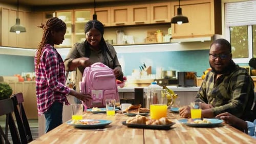 African American Mother Packing Lunch Box for Her Two School Kids