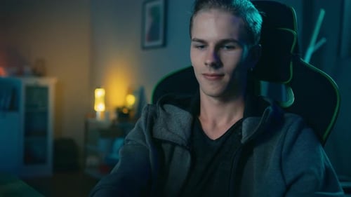 Young Man Puts On Gaming Headset in Dark Room