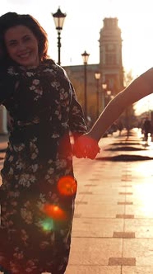 Vertical of Playful Happy Young Couple is Jumping Down the Street and Laughing