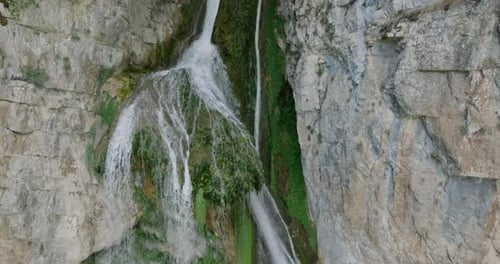 A waterfall falling from a stone cliff in the forest. Aerial view of nature.