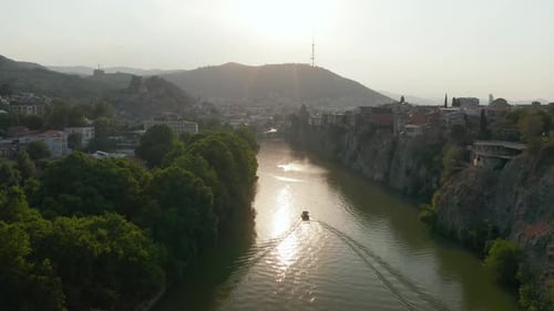 Aerial view of a river in downtown Tbilisi, Georgia at sunset, sunrise with mountains in the backgro