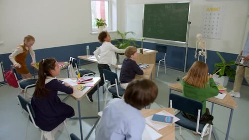 Elementary School Class Children Communicate with the Teacher Answering Question