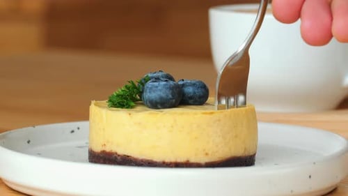 Eating Cheesecake Dessert with Blueberries and Coffee