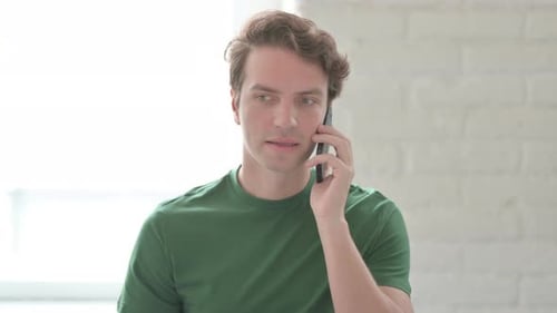 Junger Mann telefoniert über Arbeit