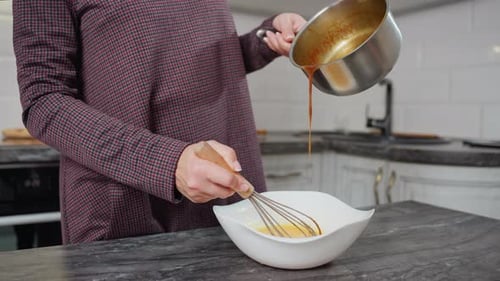 Ei umrühren, während heiße Suppe aus dem Topf in eine Schüssel in eine moderne Küche gegossen wird