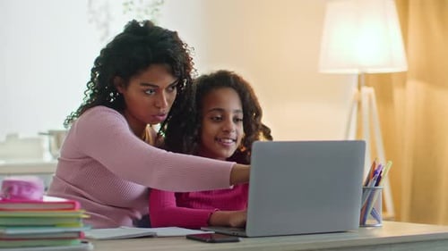 Woman and girl using laptop together at home