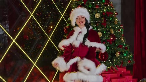 Woman in Santa Costume Dances near Christmas Tree