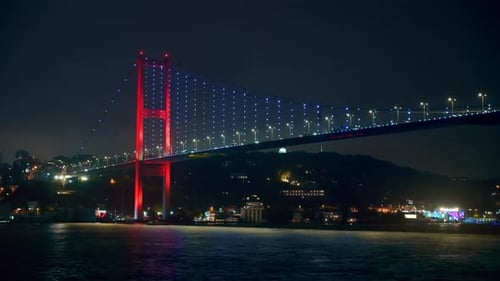 View of Bosphorus Bridge at night in Istanbul, Turkey. View from a floating ship, illumination, movi