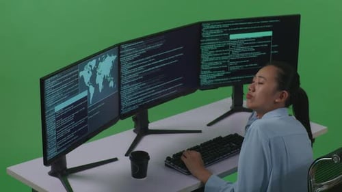 Side View Of Bored Asian Woman Developer Write Code With Multiple Computer Screens In Green Screen