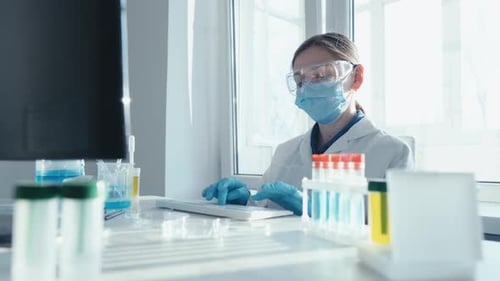 Scientist Typing at Computer in a Bright Laboratory