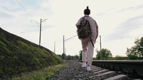 A Traveler is Walking Along the Train Tracks Surrounded By Beautiful Nature and Scenery