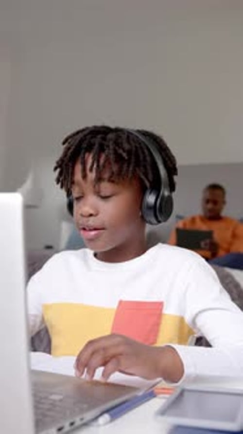 Boy with Headphones Studying at Home on Laptop