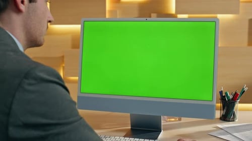Man Working at Computer with Green Screen Monitor