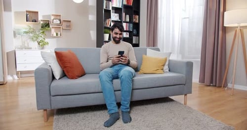 Man Using Smartphone Sitting on Couch at Home