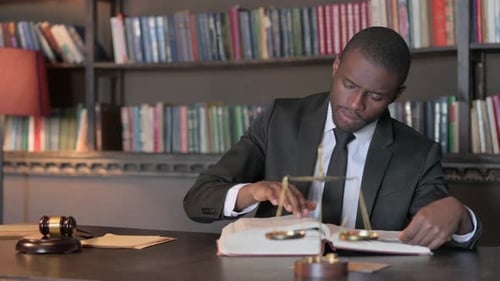Pensive African American Lawyer Reading Book in Office