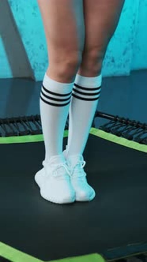 Close-up of legs of energetic young fitness girl in white sneakers who walks to mobile mini trampoli