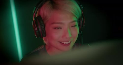 Smiling Gamer with Headphones Looking at Screen