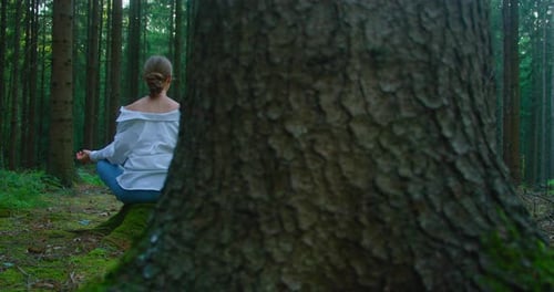 Woman Meditating on Stump in Lush Green Forest