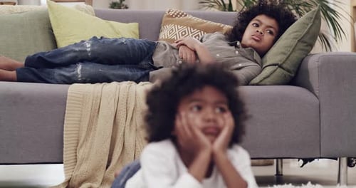 4k video footage of an adorable young boy lying on the floor at home and watching a movie