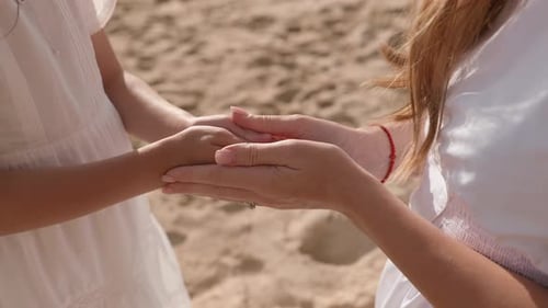 Child and Adult Hold Hands on Beach