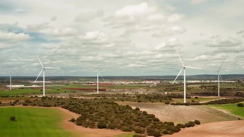 Aerial Drone View of Wind Turbines Standing Across Open Farmland Under Cloudy Sky
