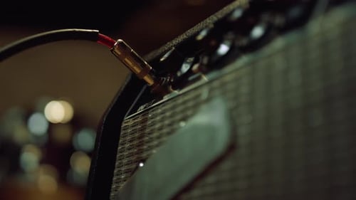 Man sticking plug to amplifier on control desk in music recording studio