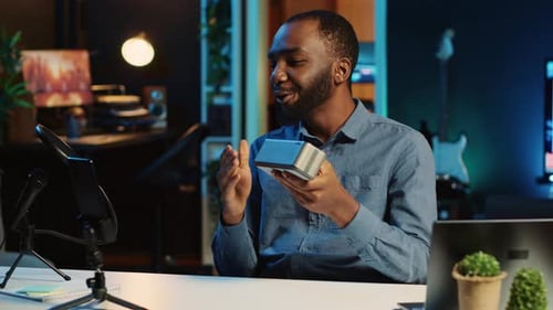 Man Reviewing Bluetooth Speaker at Desk