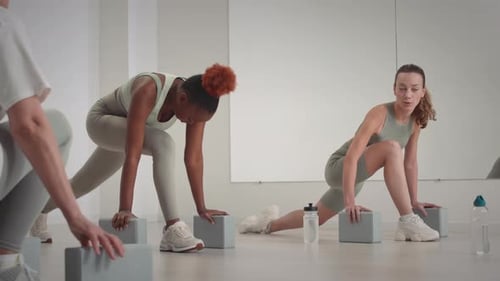Diverse Women Using Blocks while Stretching in Studio