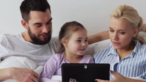 Family looking at tablet in bed at home