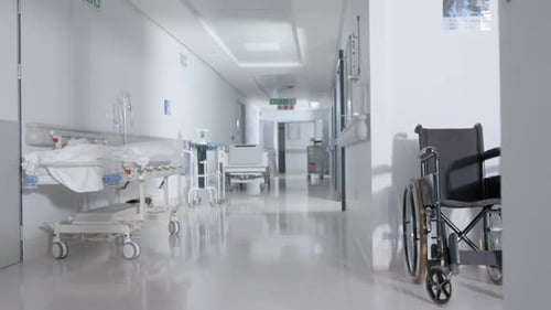 General view of empty hospital corridor with wheelchair and patient beds in slow motion