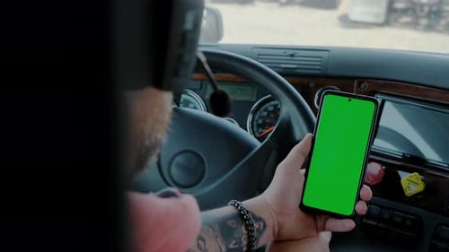 The Driver in the Truck Holds a Phone with a Green Screen in His Hands