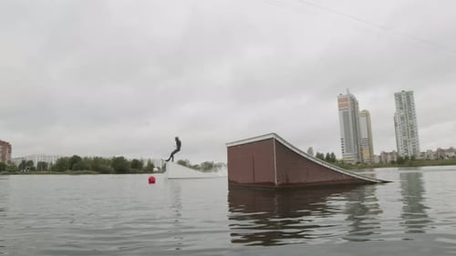 Wakeboarder Performing Stunts on Water Ramp