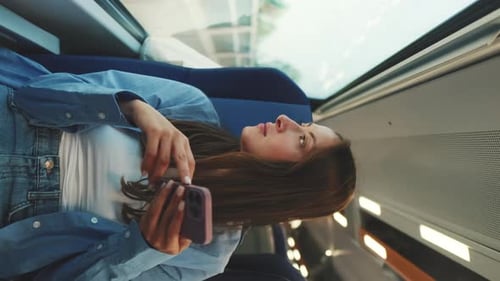 Junge Frau reist mit der S-Bahn und benutzt Handy