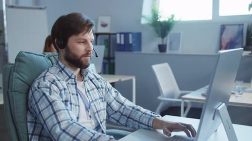 A Bearded Man in an Office Shows Focus and Excitement at Work