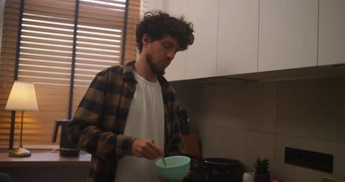 Man Stirring Food in Bowl in Kitchen