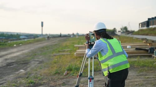 African American Surveyor Using a Theodolite on a Construction Site