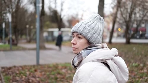 Portrait of Mature Woman in Wool Hat Standing on the Urban Street with Mobile Phone in Hand