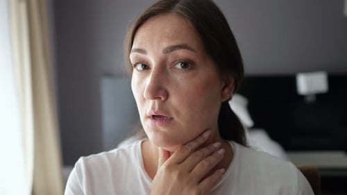 Woman Examines Neck Sagging Skin Looking Closely in Mirror
