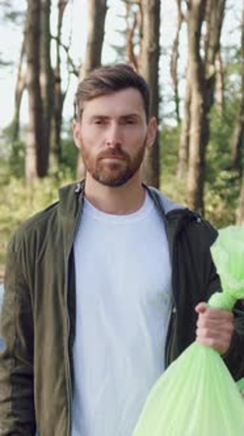 Man Carries Trash Bag With Cleanup Group in Forest