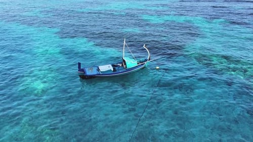 Aerial view of a blue traditional boat in clear water, Maldives.