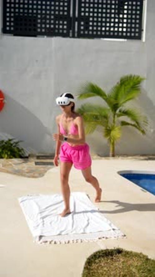 A Young Woman is Having Fun Using a VR Headset Outdoors Near a Pool on a Sunny Day