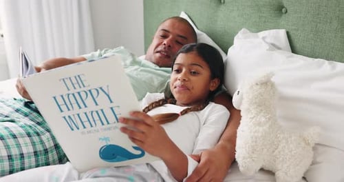 Father and Daughter Reading a Book in Bed