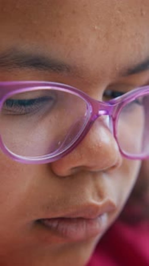 Jeune enfant concentré sur l'activité tout en portant des lunettes violettes dans un environnement intérieur lumineux