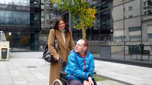 Caregiver assisting disabled man in wheelchair in the city